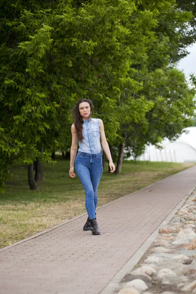 Menina bonita nova em jeans azuis e uma camisa azul no backg — Fotografia de Stock