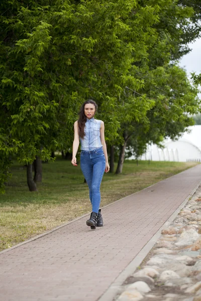 Menina bonita nova em jeans azuis e uma camisa azul no backg — Fotografia de Stock