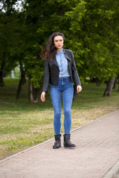 Joven hermosa chica en pantalones vaqueros azules y una camisa azul en la espalda — Foto de Stock