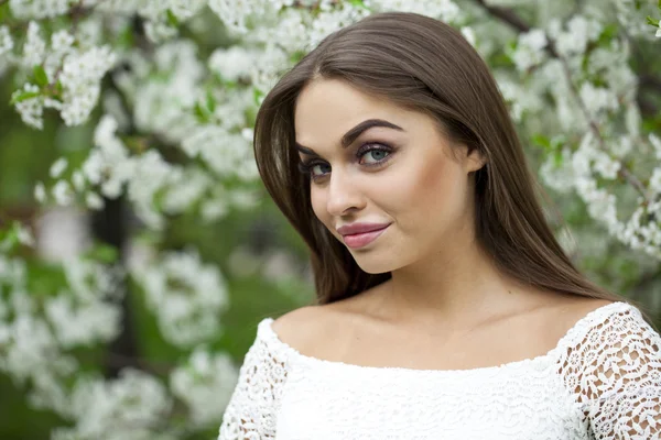 Happy young woman in white dress against the background spring f — Stock Photo, Image