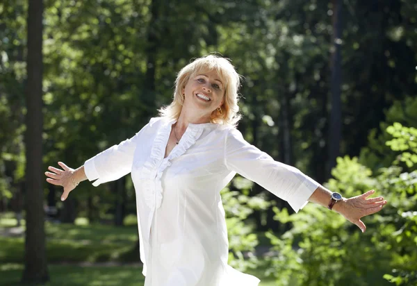 Porträtt av härlig mitten äldre kvinna i parken sommaren — Stockfoto