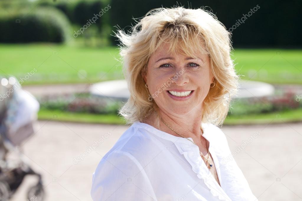 Portrait of serene mature woman in the summer park 