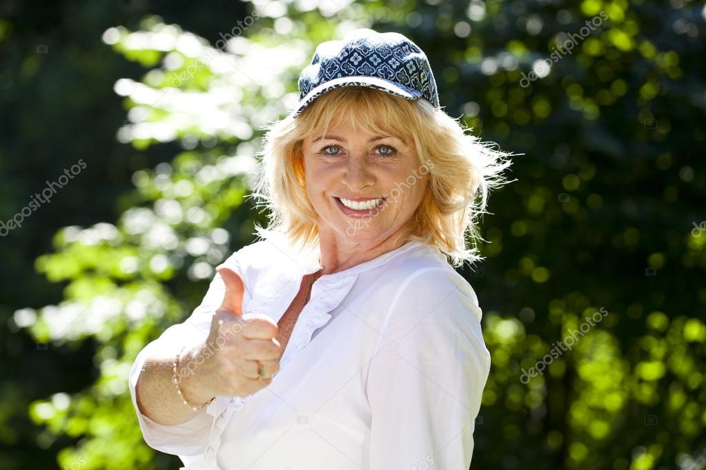 Portrait of serene mature woman in the summer park 