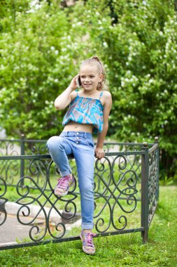 Yeşil park summe karşı cep telefonuyla konuşan küçük kız