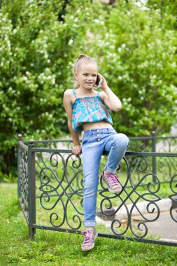 Yeşil park summe karşı cep telefonuyla konuşan küçük kız