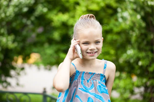 Yeşil park summe karşı cep telefonuyla konuşan küçük kız — Stok fotoğraf