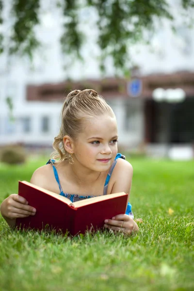 外面的草地上读书的可爱可爱的小女孩 — 图库照片