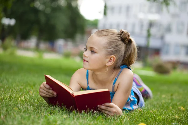 Adorable cute little girl reading book outside on grass — Stock Photo, Image