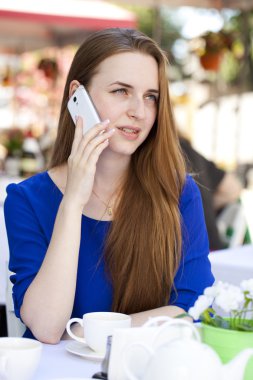 Pretty young blonde woman sitting in the cafe and calling by pho