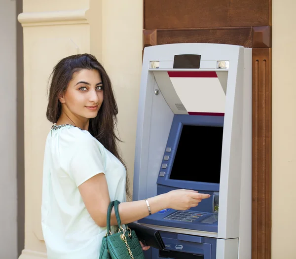 Giovane donna in jeans breve utilizzando un sportello automatico — Foto Stock