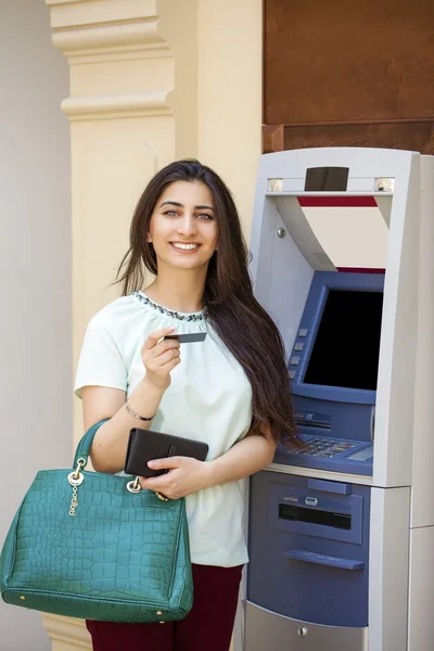 Mujer joven en pantalones vaqueros cortos usando un cajero automático — Foto de Stock