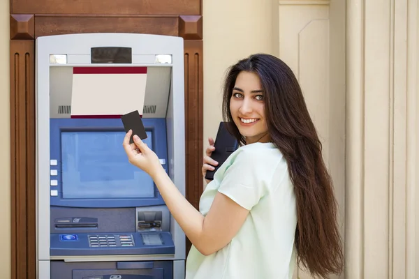 Mujer joven en pantalones vaqueros cortos usando un cajero automático — Foto de Stock