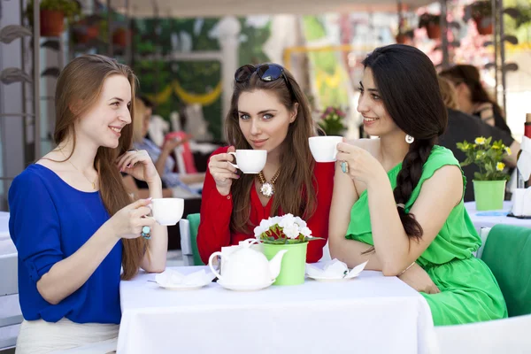 Drie gelukkige vriendinnen vrouw zitten aan een tafel in de zomer c — Stockfoto