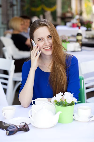 Bella giovane donna bionda seduta nel caffè e chiamando da pho — Foto Stock