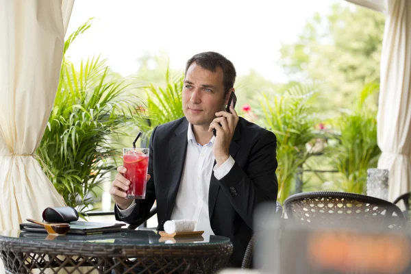 Empresário falando em um telefone celular e bebendo um coquetel — Fotografia de Stock