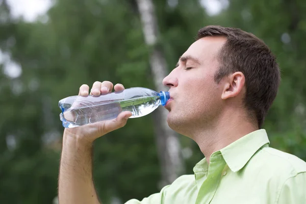 Schöner Mann, der Wasser in einem Park trinkt — Stockfoto