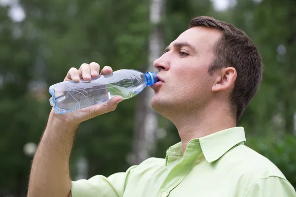 Yakışıklı adam içme suyu bir parkta — Stok fotoğraf