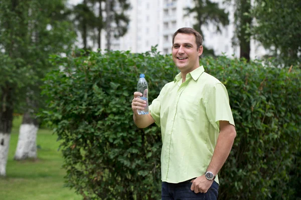 Bell'uomo che beve acqua in un parco — Foto Stock