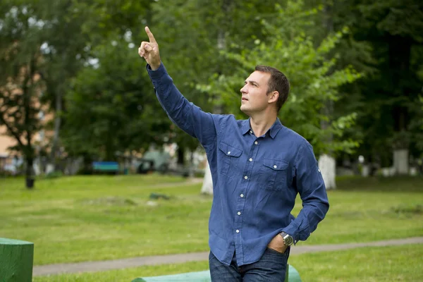 A young handsome man points his finger to the side — Stock Photo, Image