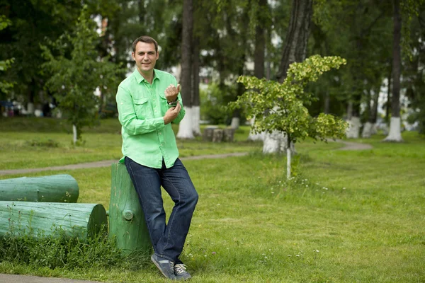 Jovem homem bonito em uma camisa verde no fundo do verão — Fotografia de Stock