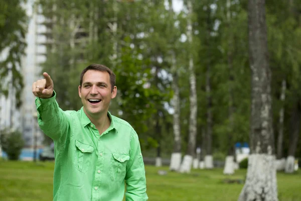 Ein junger gutaussehender Mann zeigt mit dem Finger zur Seite — Stockfoto