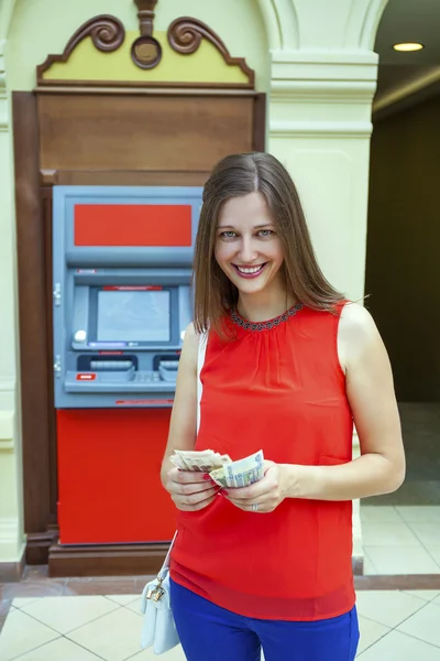 Молода жінка знімати гроші з кредитної картки в банкоматі — стокове фото