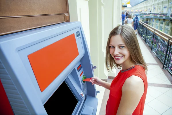 Молодая женщина снимает деньги с кредитной карты в банкомате — стоковое фото