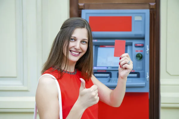 Молодая женщина снимает деньги с кредитной карты в банкомате — стоковое фото