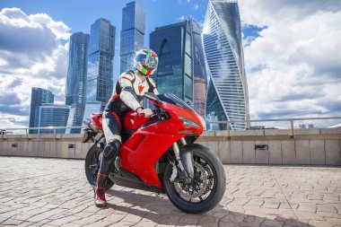 Tam büyüme portre, spor motor şehir manzarası ve mavi gökyüzü arka plan üzerinde genç adam oturur