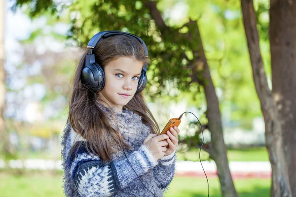 Belle petite fille écoutant de la musique sur écouteurs — Photo