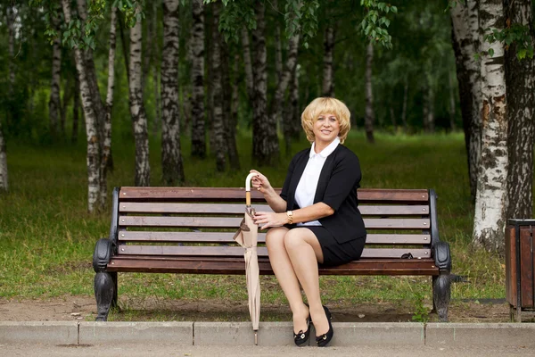 Ältere Geschäftsfrau im Sakko sitzt auf Bank — Stockfoto