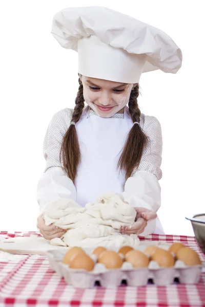 Menina em um avental branco e chapéu de chefs amassar a massa em th — Fotografia de Stock