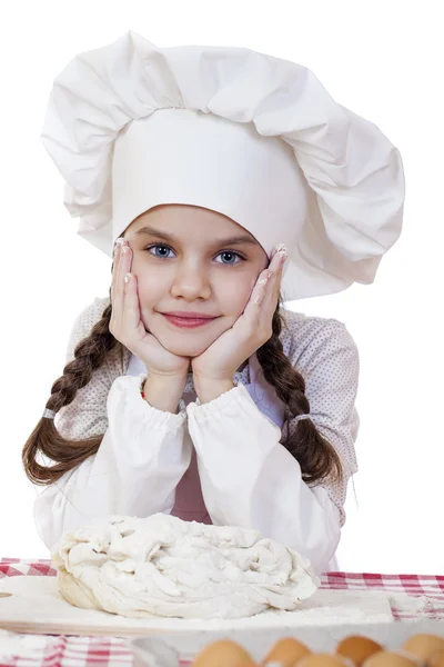 小女孩穿着白色围裙和厨师的帽子揉面团在 th — 图库照片