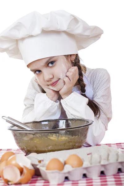 Kleines Mädchen in weißer Schürze und Kochmütze kneten den Teig im — Stockfoto