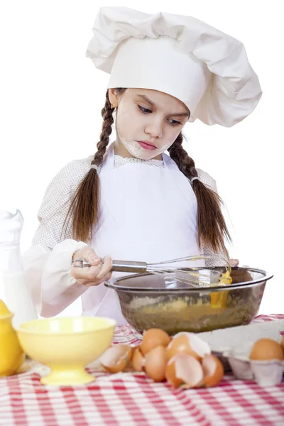 Kleines Mädchen in weißer Schürze und Kochmütze kneten den Teig im — Stockfoto