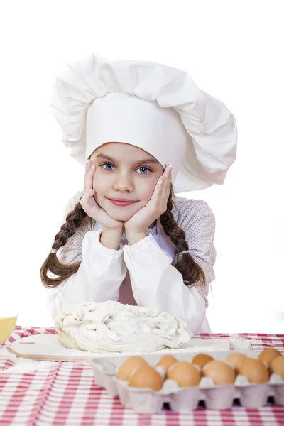 Niña en un delantal blanco y chefs sombrero amasar la masa en th — Foto de Stock