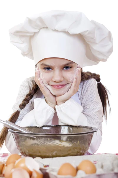 小女孩穿着白色围裙和厨师的帽子揉面团在 th — 图库照片