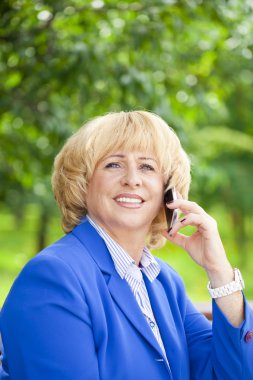 Bir cep telefonuyla konuşan yaşlı bir güzel kadın portresi 