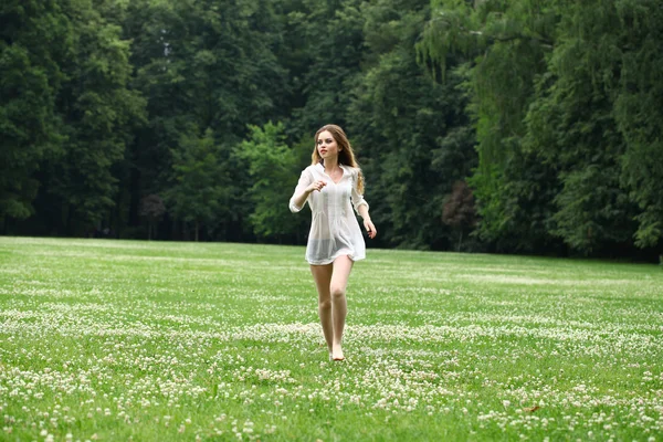 Joven hermosa chica en la camisa blanca se ejecuta en el verde —  Fotos de Stock