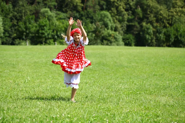 Liten flicka i en röd prickiga sundress in en större körningen på den — Stockfoto