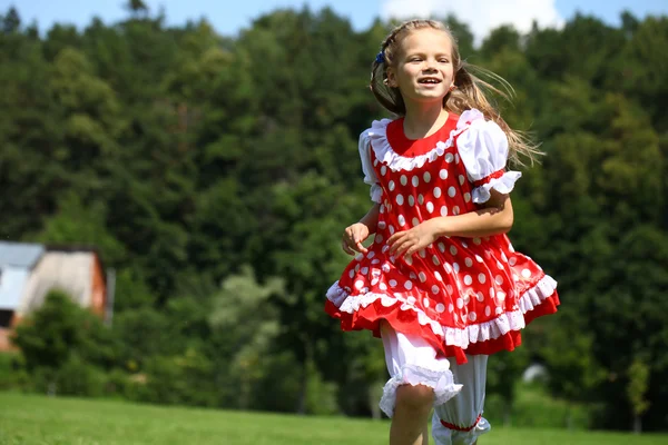 Liten flicka i en röd prickiga sundress in en större körningen på den — Stockfoto