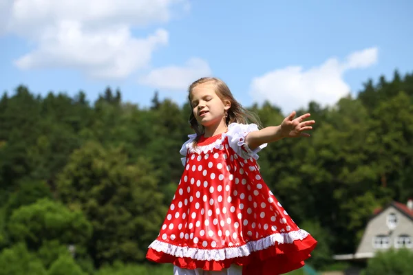 Kırmızı benekli sundress üzerinde büyük bir çalışma içine, küçük kız — Stok fotoğraf