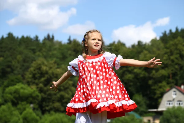 Kleines Mädchen in einem roten Tupfen-Outfit in einen großen Ansturm auf die — Stockfoto