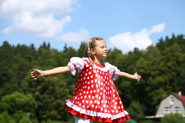 Kleines Mädchen in einem roten Tupfen-Outfit in einen großen Ansturm auf die — Stockfoto