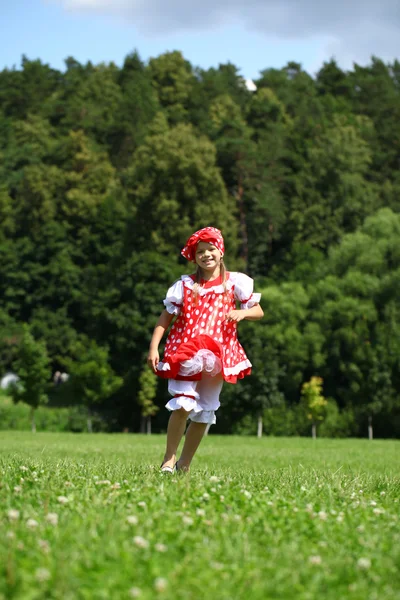 Ragazzina in un abito da sole a pois rosso in una grande corsa sul — Foto Stock