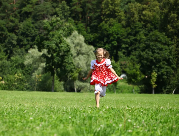 Liten flicka i en röd prickiga sundress in en större körningen på den — Stockfoto