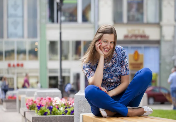 Jovem mulher bonita feliz senta-se em um banco — Fotografia de Stock