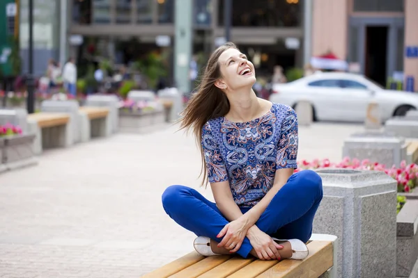 Jovem mulher bonita feliz senta-se em um banco — Fotografia de Stock