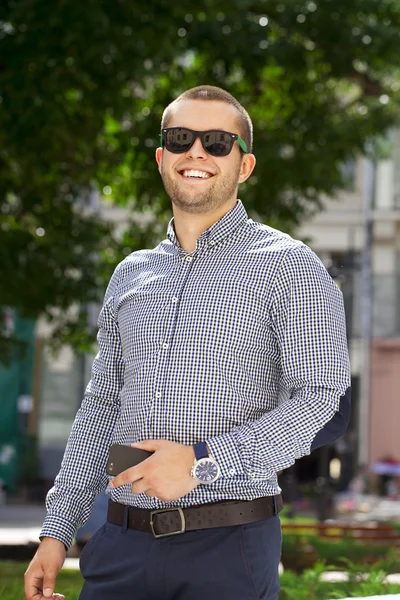 Young handsome man in in plaid shirt on the background of summer — Stock Photo, Image