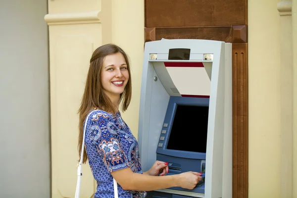 Jonge vrouw in zomerjurk met behulp van een automated teller machine — Stockfoto
